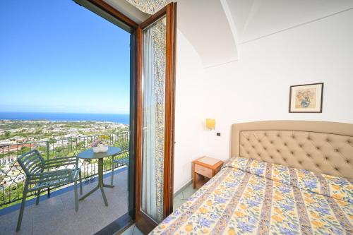 a bedroom with a bed and a balcony with a view at La Capannina - Hotel & Apartments in Ischia Town