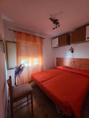 a bedroom with a red bed and a fan at La casa di Claudia Torre Suda in Torre Suda