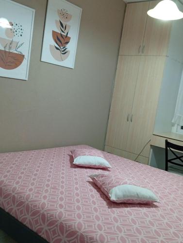 a bedroom with a pink bed with two pillows at AGAPI'S HOUSE in Sidirokastro