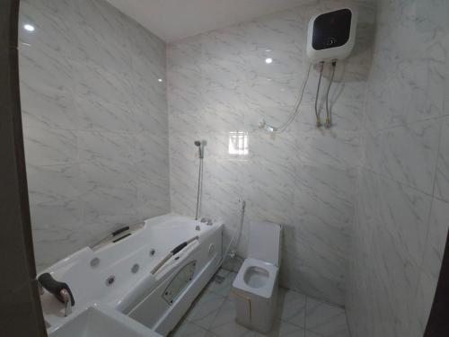 a white bathroom with a tub and a toilet at House 27 Crown in Idu