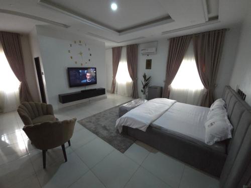 a bedroom with a bed and a tv and a chair at House 27 Crown in Idu