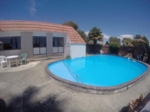 a large blue swimming pool in front of a house at Opotiki Holiday Park in Opotiki