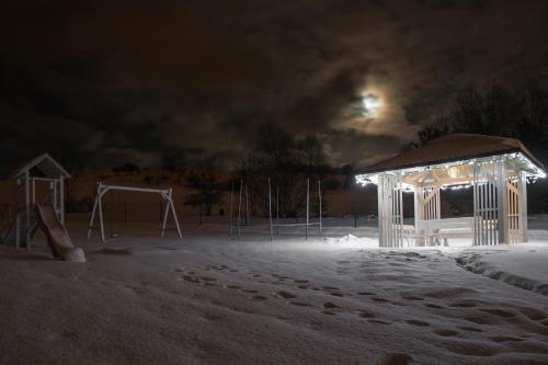 a playground with a gazebo in the snow at night at Apartamenty U Harrego I Przy Stawie Spa z klimatyzacją, balia, sauna, ogrodem i parkingiem in Kudowa-Zdrój