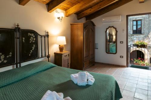 a bedroom with a green bed with towels on it at Il Castello di San Sergio in Centola