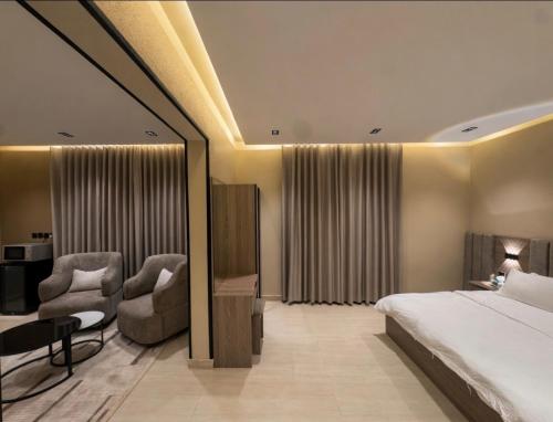 a hotel room with a bed and two chairs at Bluestone Amlak 1 in Medina