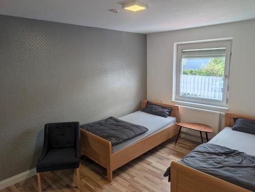 a room with two beds and a chair and a window at Private Apartment centrally located in Grafenwöhr