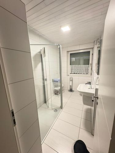 a white bathroom with a shower and a sink at Private Apartment centrally located in Grafenwöhr