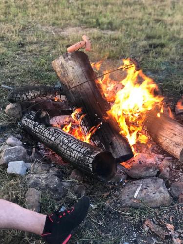 a campfire with logs and a person standing next to it at Chatka u Radka in Radacz