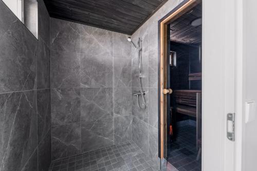 a bathroom with a shower with gray tiles at Villa Rantakukka Koli, oma ranta in Kolinkylä