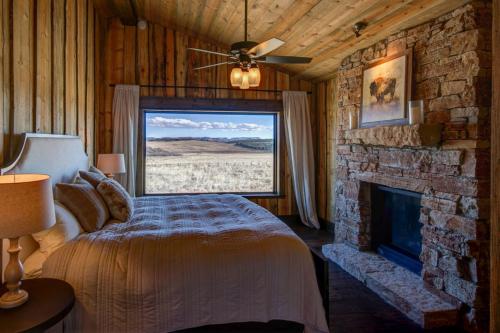 a bedroom with a fireplace and a bed in front of a window at Zion Mountain Ranch in Mount Carmel Junction