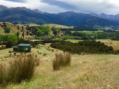 a small cabin on a hill with mountains in the background at Manakau PurePod in Kaikoura