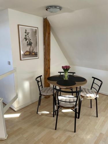 a dining room table with chairs and a vase of flowers at The White Farm in Skanderborg