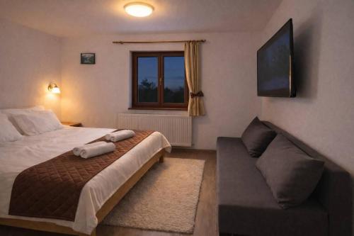 a bedroom with a bed and a couch and a window at Hódvár Apartman in Tiszafüred