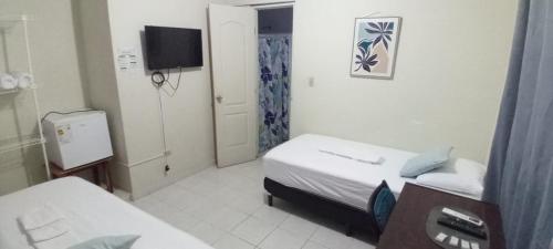 a small room with two beds and a tv at Habitación en Casa Las Palmitas in Penonomé