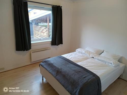 a bedroom with a bed and a window with black curtains at Sentrumsnær leilighet in Trondheim