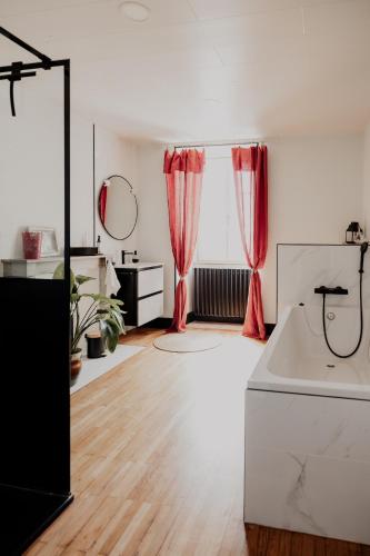 a living room with red curtains and a hardwood floor at L' Ecrin de Suzanne-Maison de 180M2 avec sauna et bain nordique privatifs in Ray-sur-Saône
