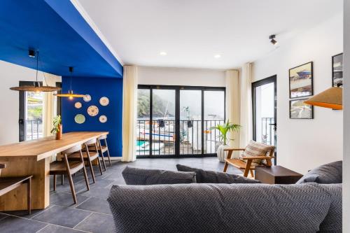a dining room and living room with a blue wall at Casa do Porto - Santa Cruz B&B in Ribeiras