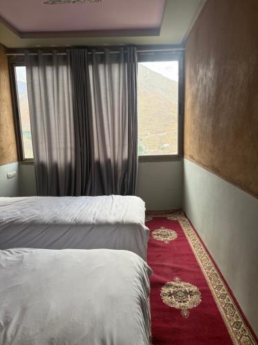 a bedroom with two beds and a window at Berber lodge amssouzart in Tizgui