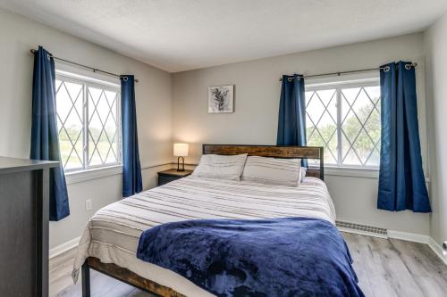 a bedroom with a large bed with blue curtains at Lake Huron Launchpad! Creekfront Condo for Two in Port Huron