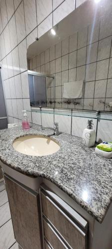 a bathroom counter with a sink and a mirror at Casa grande com suite in São Luís
