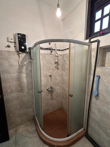 a shower with a glass door in a bathroom at Ceylander Suites in Kandy