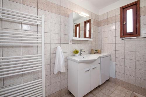 a white bathroom with a sink and a mirror at Fiore Marino in Kamisianá