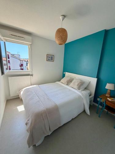 a bedroom with a large bed and a blue wall at Pays Basque Ciboure - calme, port & plages à pied in Ciboure