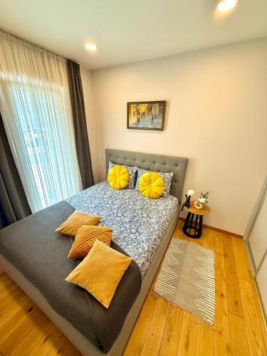 a bedroom with a bed with yellow pillows and a window at Matas old town apartment in Kaunas