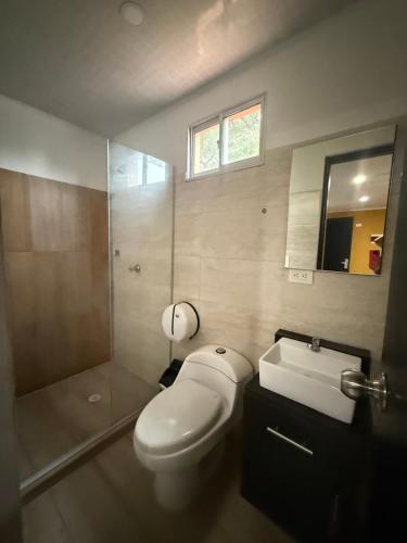a bathroom with a toilet and a shower and a sink at Hotel Paranawa in Baranoa