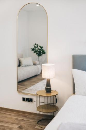 a mirror in a bedroom with a bed and a table with a lamp at Residenz am Altmarkt in Löbau