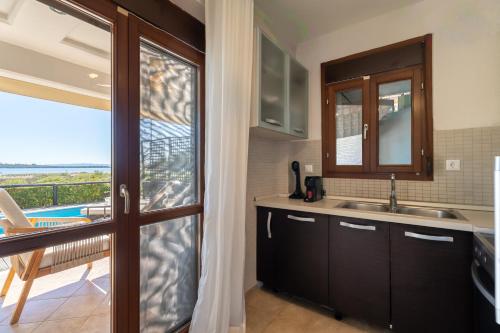 a kitchen with a sink and a sliding glass door at Villa Malvina in Neos Marmaras