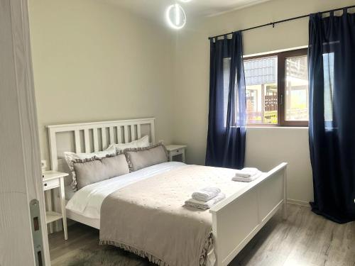 a white bedroom with a bed and a window at Mountain Stream Serenity - AC and Free Parking in Buşteni