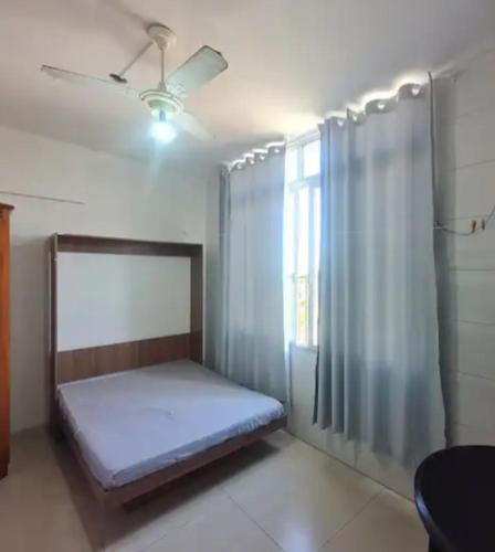 a bedroom with a bed with a ceiling fan and a window at Guarapari com elevador, reformado, Wi-Fi, TV com Smart, vista livre e estacionamento in Guarapari