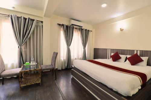 a hotel room with a large bed and a table at Hotel Pun Inn Kathmandu in Kathmandu