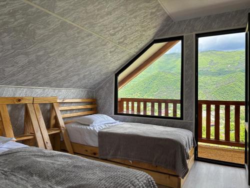 two beds in a room with a large window at Racha Hills in Ambrolauri