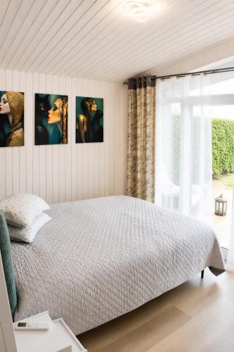 a bedroom with a bed with four pictures on the wall at Aukštupio Vila in Aukštupėnai