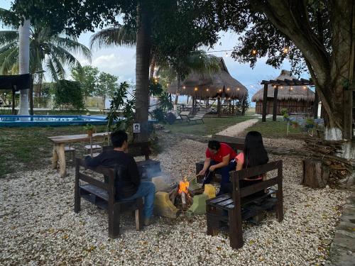 a group of people sitting around a fire in a park at Hotel Shalva Barahona in Izamal