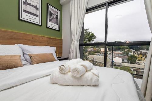 a bedroom with two towels on a bed with a window at Cabral Smart Comfort in Curitiba