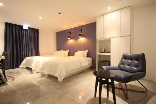 a bedroom with a white bed and a chair at SOYU Hotel in Busan