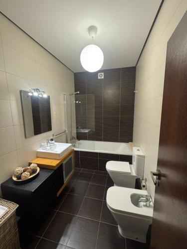 a bathroom with two toilets and a sink and a tub at Vila Praia House in Vila Praia de Âncora