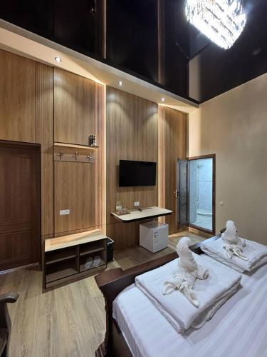 a bedroom with two beds and a desk and a television at Hotel Anor in Samarkand