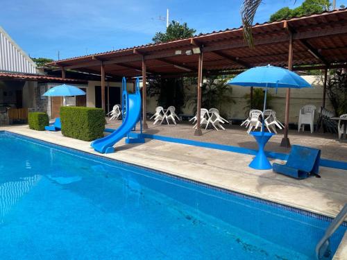 a pool with a slide and chairs and umbrellas at Hotel Oasis Beach Club in Puntarenas