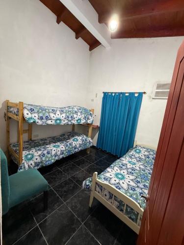 a room with two beds and a blue curtain at Esquina Hostel in Esquina