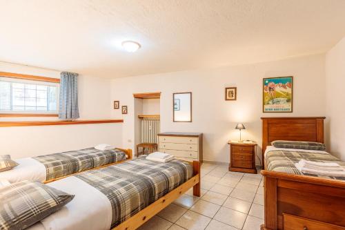 a bedroom with two beds and a desk at Maison Jaccod_piano terra in Morgex
