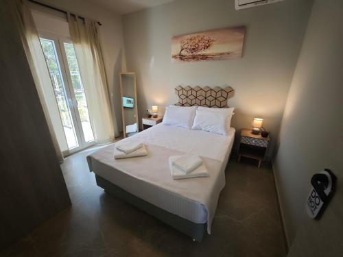 a bedroom with a large bed with two towels on it at Μπαλκόνι με Θέα in Pérdika