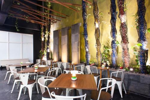 a restaurant with tables and chairs and trees on the wall at MaxOneHotels at Dharmahusada Surabaya in Surabaya