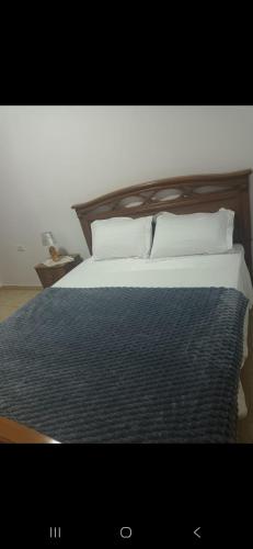 a bedroom with a bed with a wooden headboard and pillows at Vila Ameli Bucimas in Buçimas