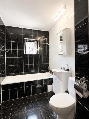 a black tiled bathroom with a toilet and a sink at Reyna Breeze Apartment in Constanţa