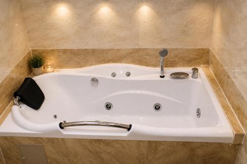 a white bath tub in a bathroom with tiles at Apartament Deluxe Bistrita in Bistriţa