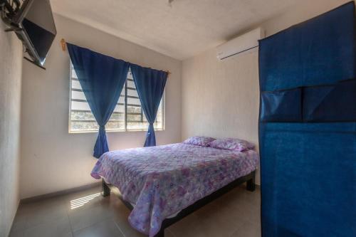 a bedroom with a bed with blue curtains and a window at Escape Turquesa in Los Algodones